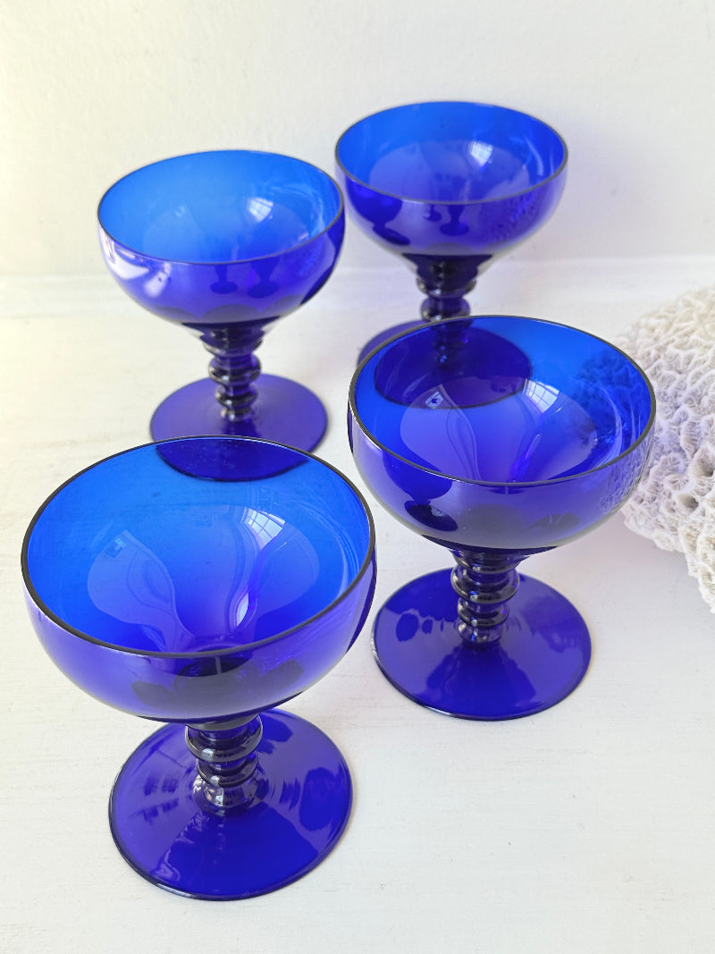 Set of four vintage cobalt blue cocktail glasses with stepped stems, photographed on a white surface