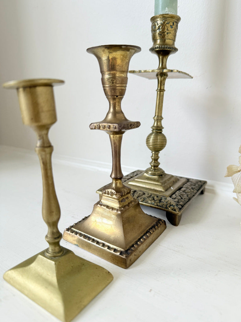 vintage brass trio of candlesticks in mixed designs photographed on white surface
