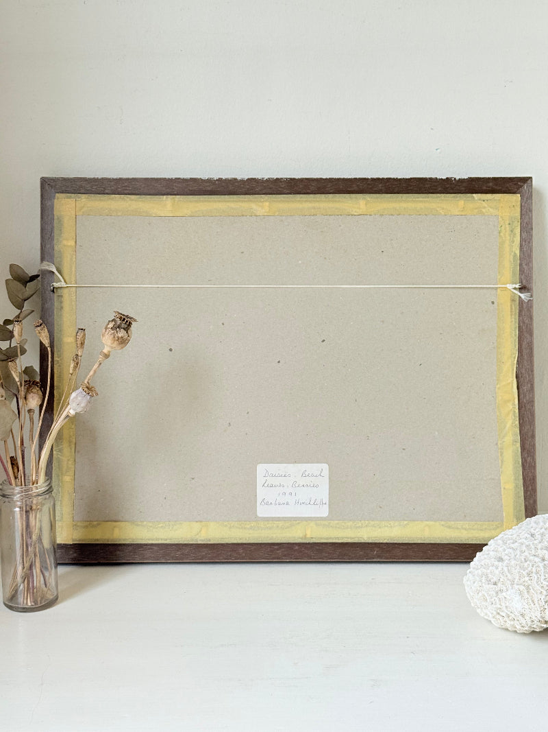 Vintage oil painting on board of daisies in a vase, framed under glass and photographed on a white surface beside dried flowers.