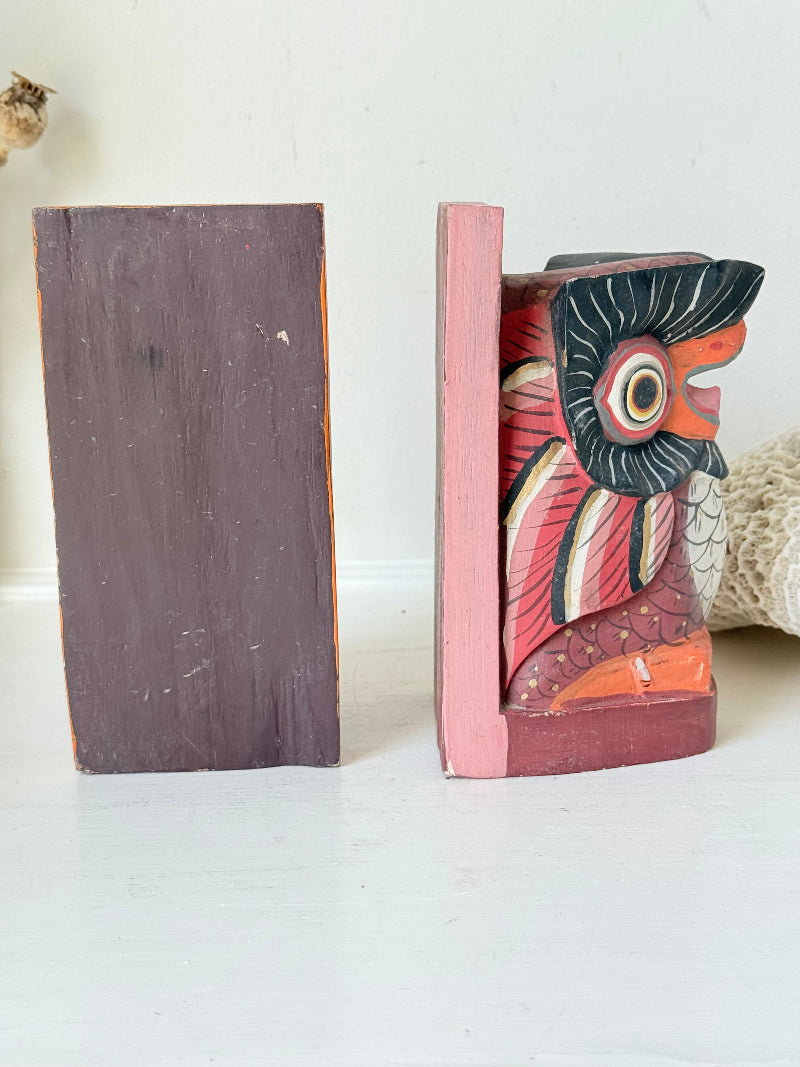 Vintage wooden owl bookends hand painted in red and orange tones, displayed on a white surface beside dried flowers.
