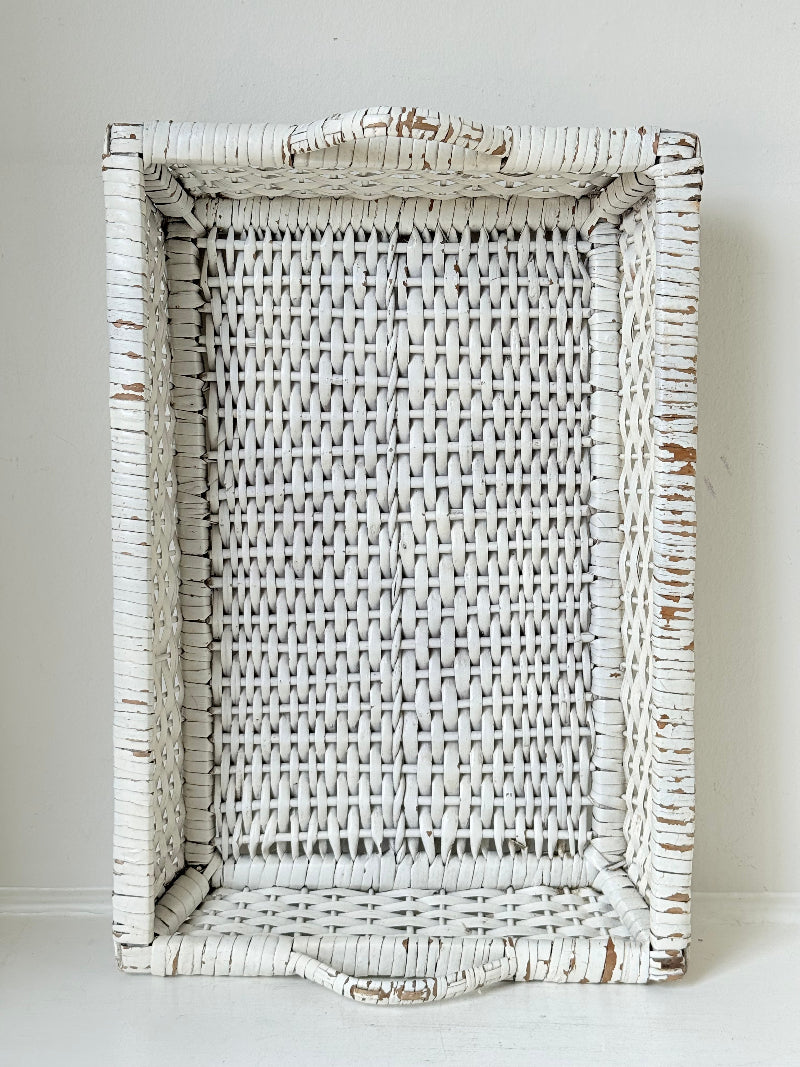 Vintage white painted wicker tray with woven handles photographed on a white surface