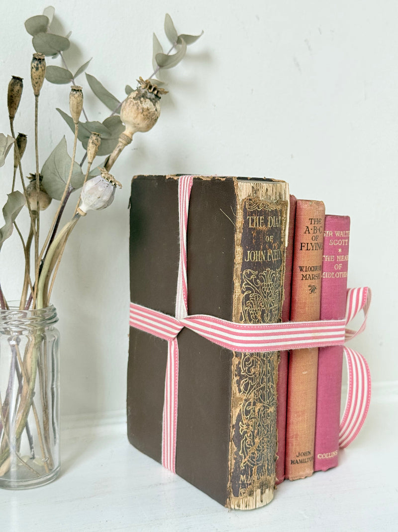 Vintage autumn colours decorative book bundle with pink ribbon, photographed on a white surface