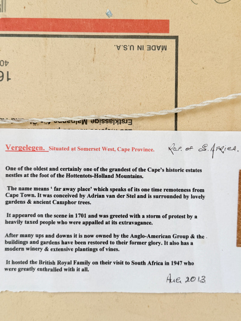 A close-up of a vintage paper document or postcard with printed text, a red stamp, and handwritten notes, laid on a tan paper background.