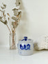 Vintage lidded pottery jar with hand painted blue floral decoration, photographed on a white surface