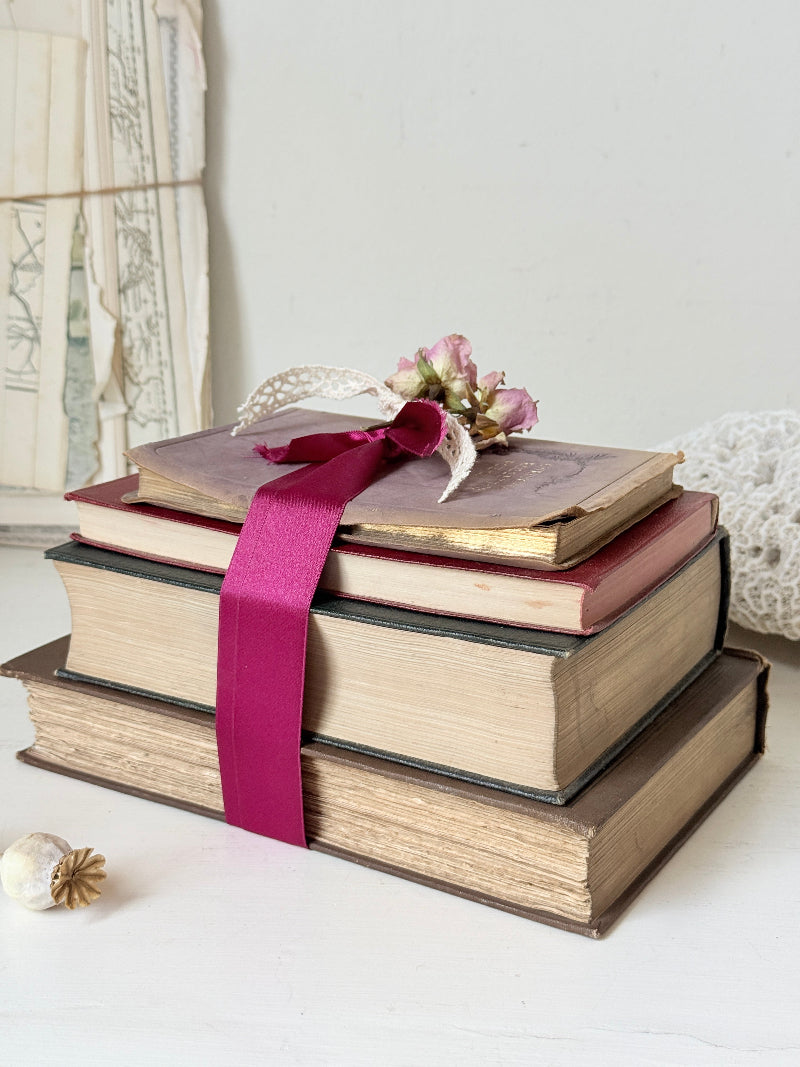 Vintage decorative book bundle with pink ribbon, dried flower detail and aged hardback covers for shelf and table styling