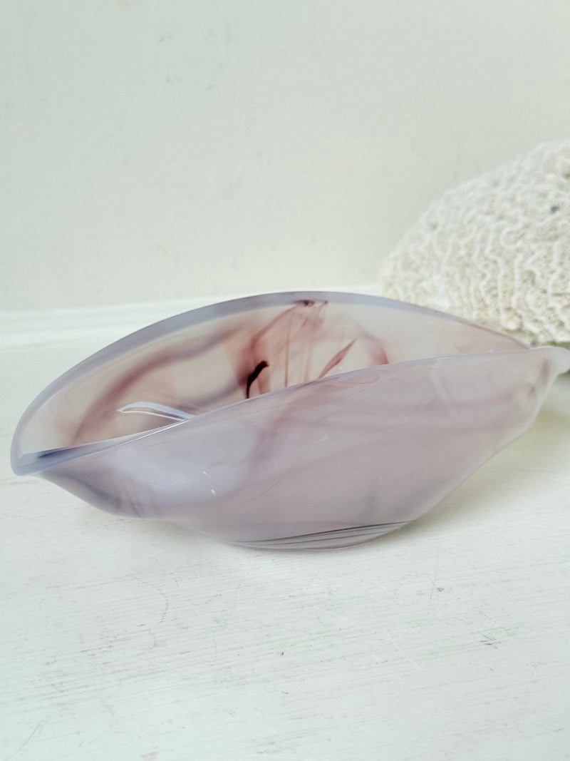 Vintage clam shaped Sowerby glass bowl in lilac purple swirl photographed on a white surface