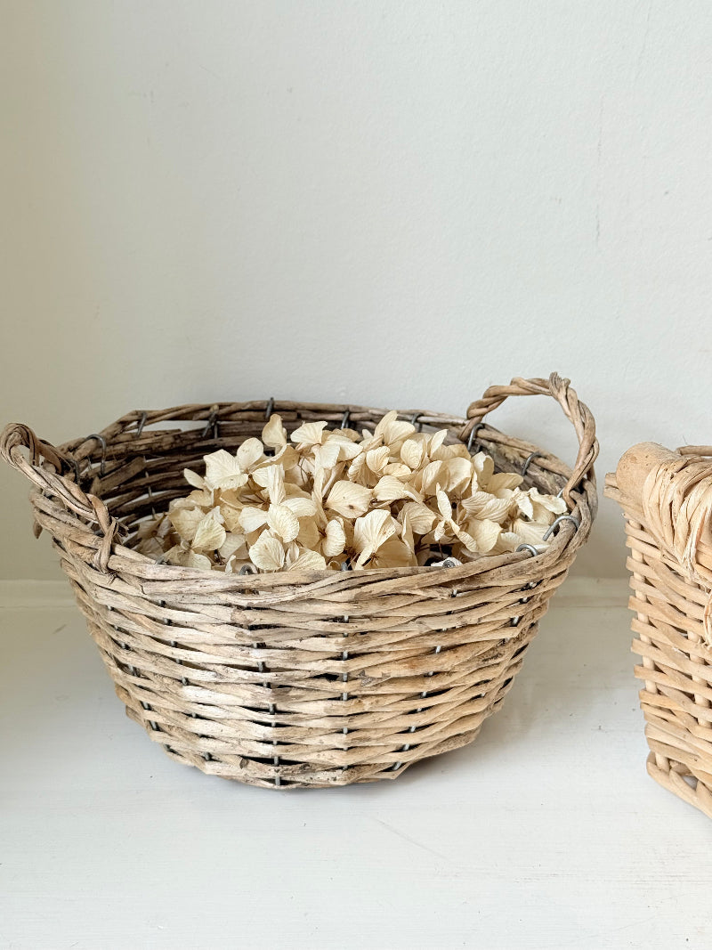 Set of three vintage woven willow baskets in natural tones photographed on a white surface