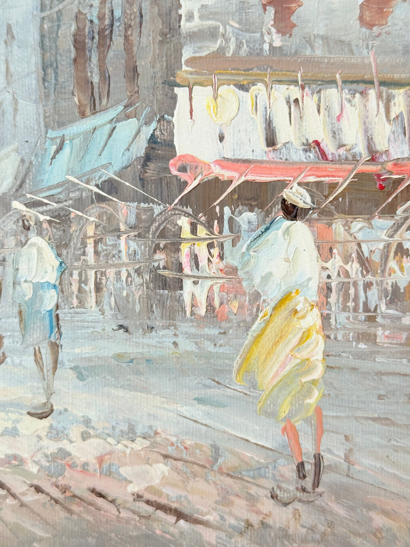 Vintage oil painting of European street scene with buildings and awnings in wooden frame photographed on a white surface