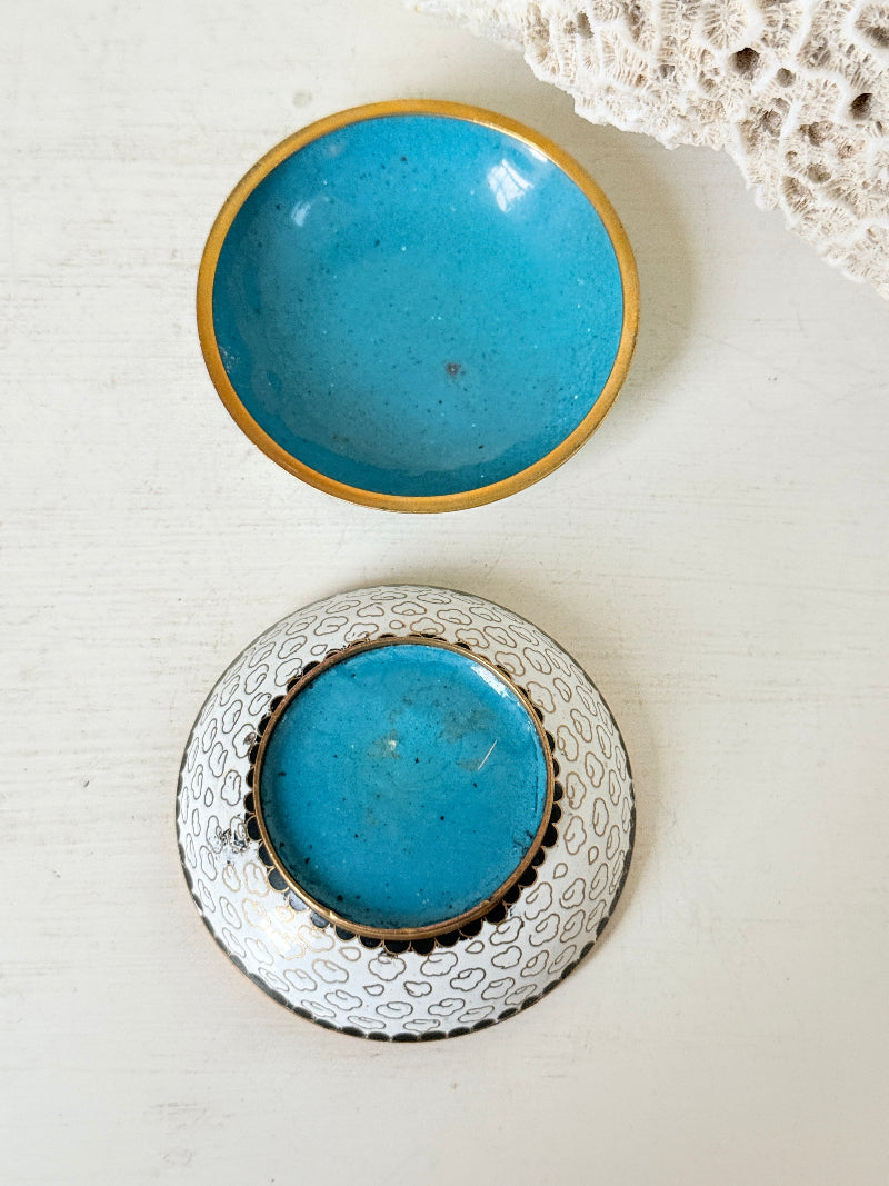 Vintage brass and enamel cloisonne trinket box with floral lid and turquoise interior photographed on a white surface
