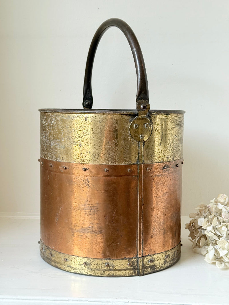 Vintage copper and brass metal bin with handle, photographed on a white surface.