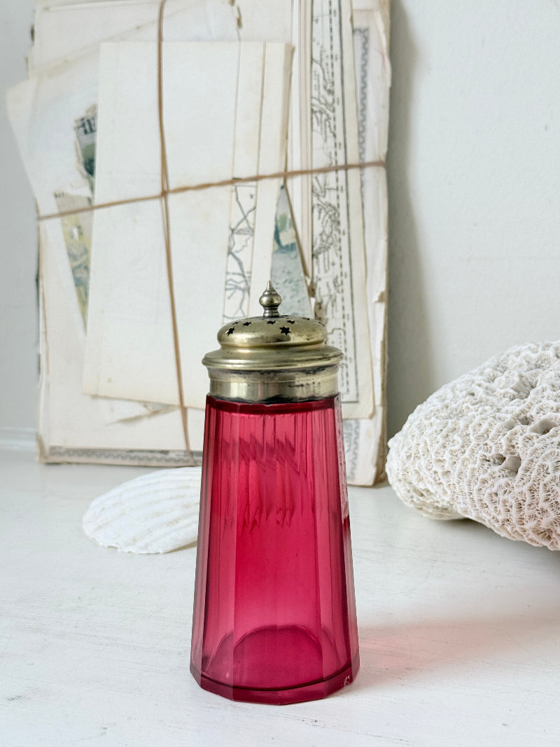 Antique cranberry glass sugar shaker with ribbed optic body, pierced metal top, star holes and deep pink glass