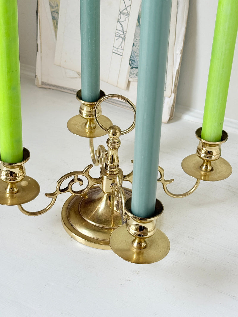 Brass five light candelabra with scrolled arms and a central ring handle on a domed base, photographed on a white surface