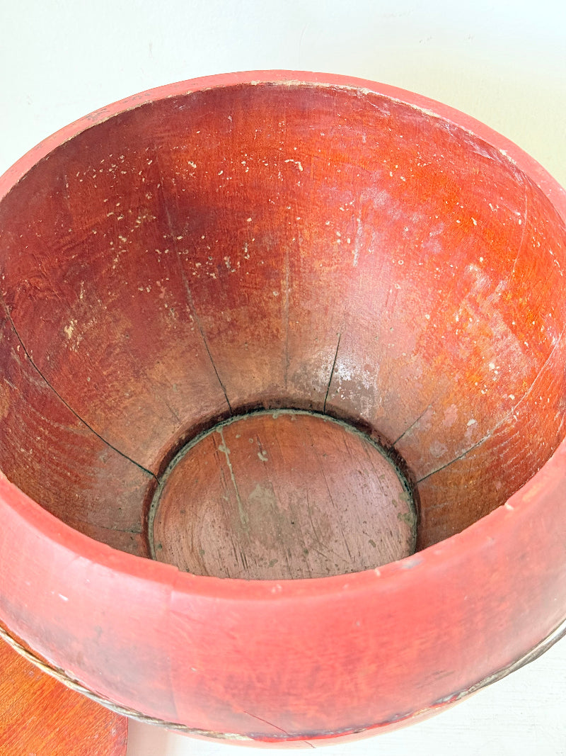 Vintage red painted wooden basket with tall curved handle and domed lid photographed on a white surface