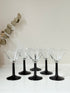 Set of six clear martini glasses with black stems, photographed on a white surface
