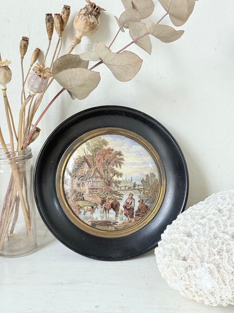 Antique Prattware framed pot lid with cottage scene photographed on a white surface.