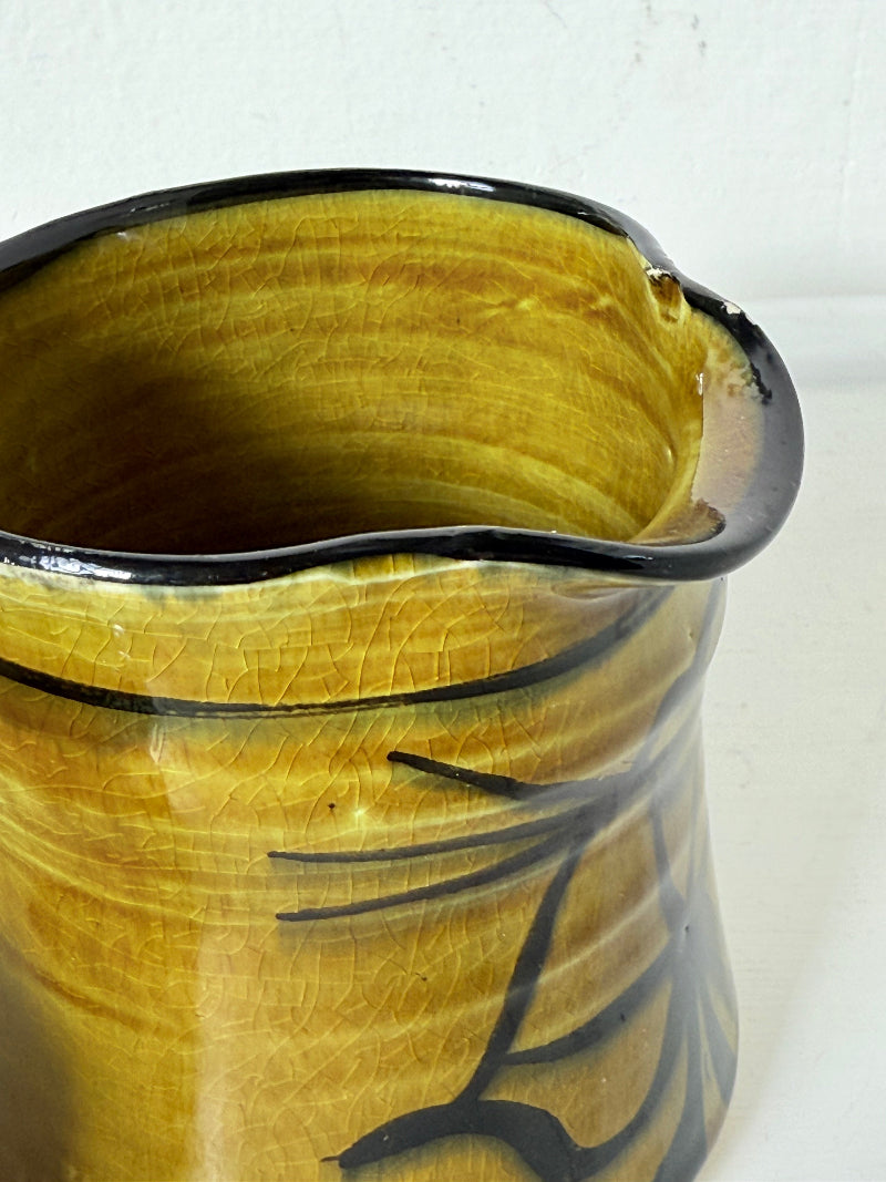 Studio pottery sugar bowl and milk jug in olive green glaze with black brushstroke decoration, photographed on a white surface.