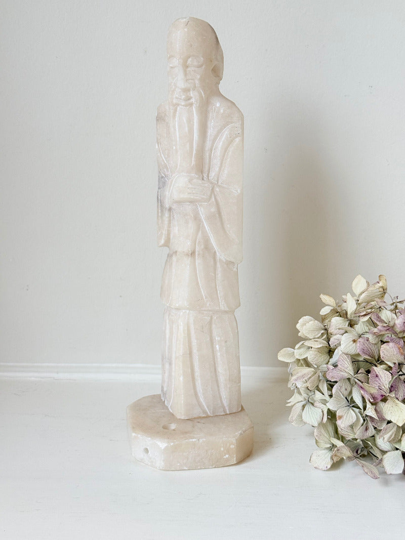 vintage alabaster gentleman figure on square base with carved detail, photographed on white surface with hydrangea flowers.