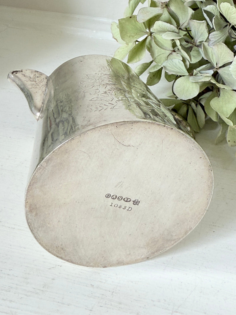 vintage silver plate jug with curved handle photographed on white surface with green hydrangeas