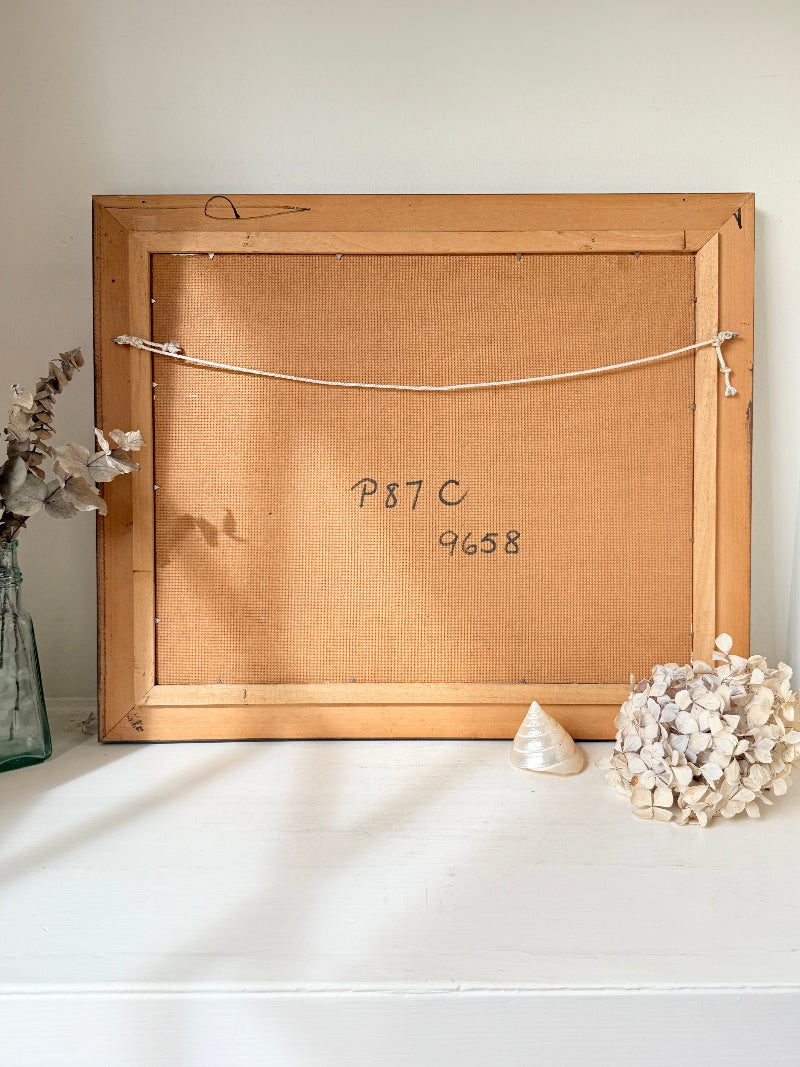 The back of a wooden picture frame leaning against a white wall on a white surface, with handwritten numbers &