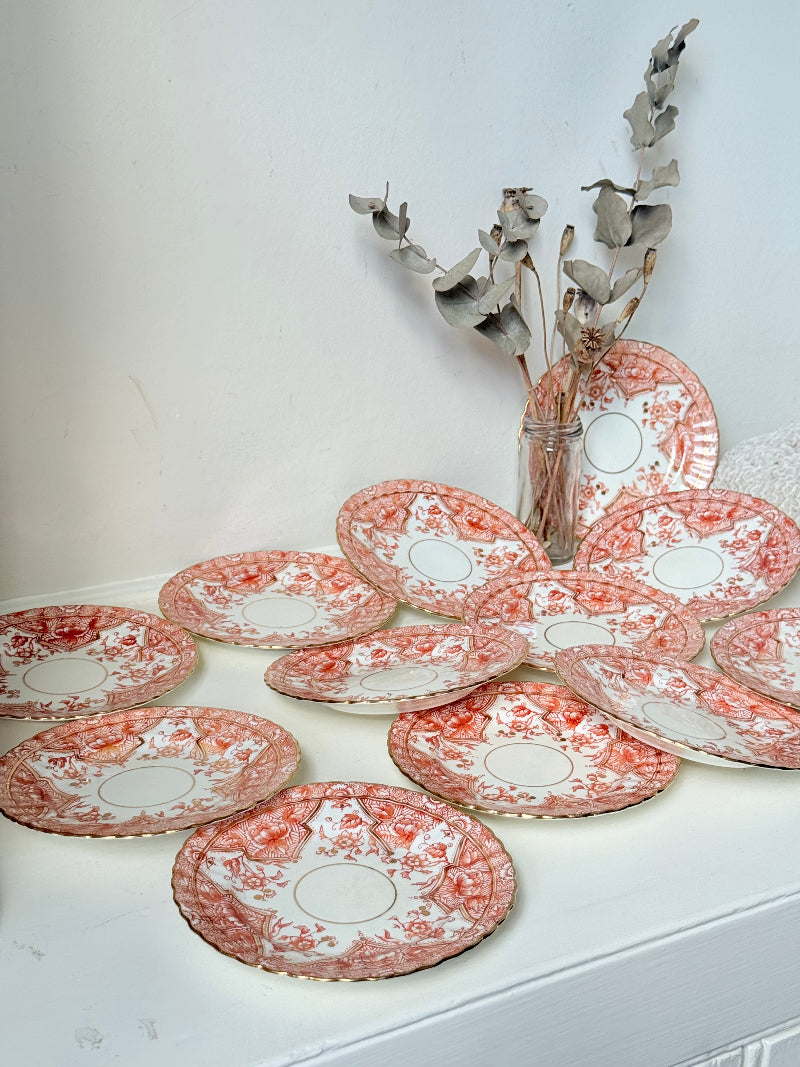 Set of 12 vintage coral transferware porcelain plates with scalloped edges and gold accents, 15 cm diameter, styled on a white surface.