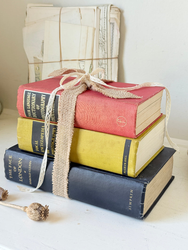 Vintage decorative book bundle in blue yellow and red with aged hardback covers tied with natural ribbon for bookshelf styling