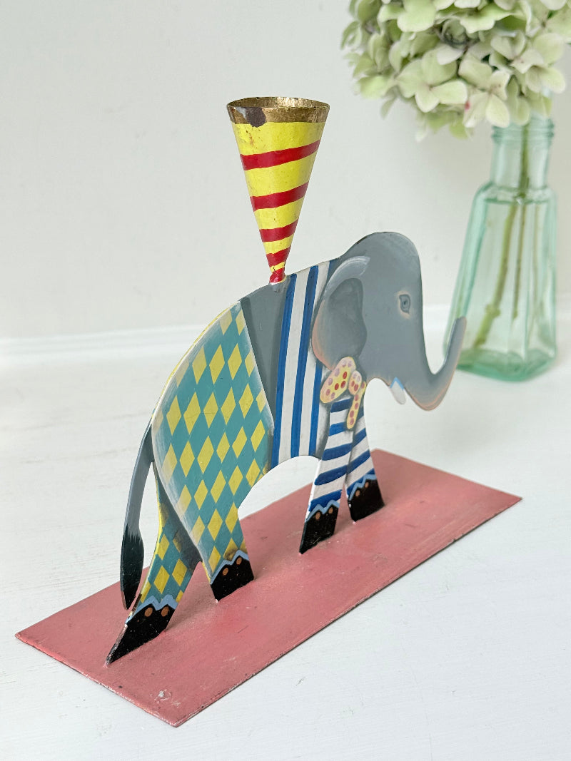 Hand painted metal elephant candlestick in circus-style decoration with colourful patterns, photographed on a white surface