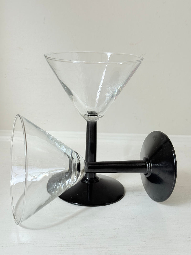 Set of six clear martini glasses with black stems, photographed on a white surface