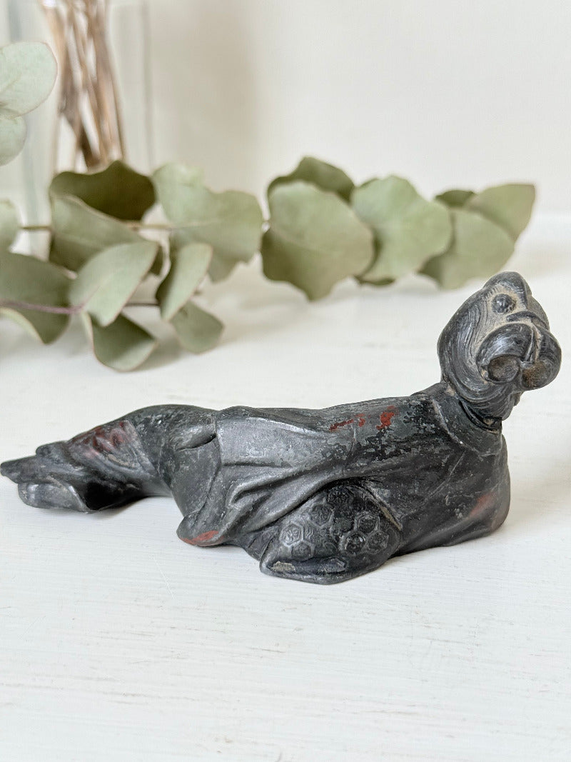 antique japanese bronze reclining lady with impressed marks to base photographed on white surface with foliage background