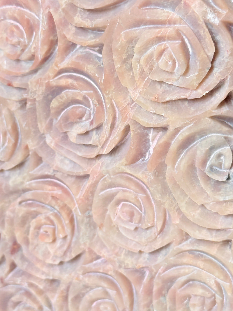 vintage pink stone heart with engraved roses and flat base on white surface