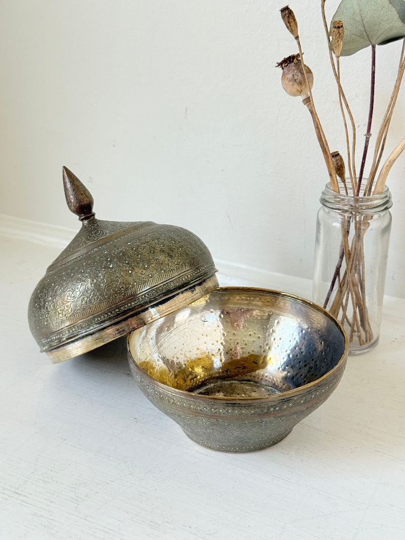 Indian Benares brass lidded jar with floral engraving and finial, photographed on a white surface