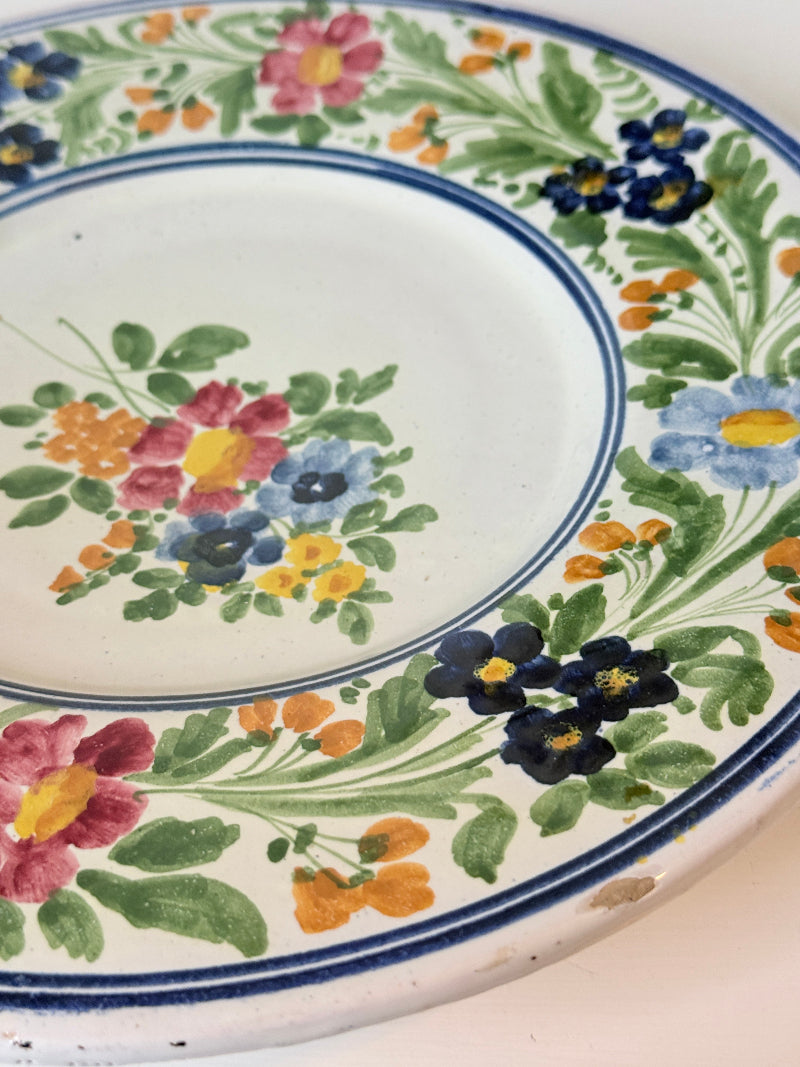Vintage Italian majolica floral plate with blue green yellow and pink decoration photographed on a white surface