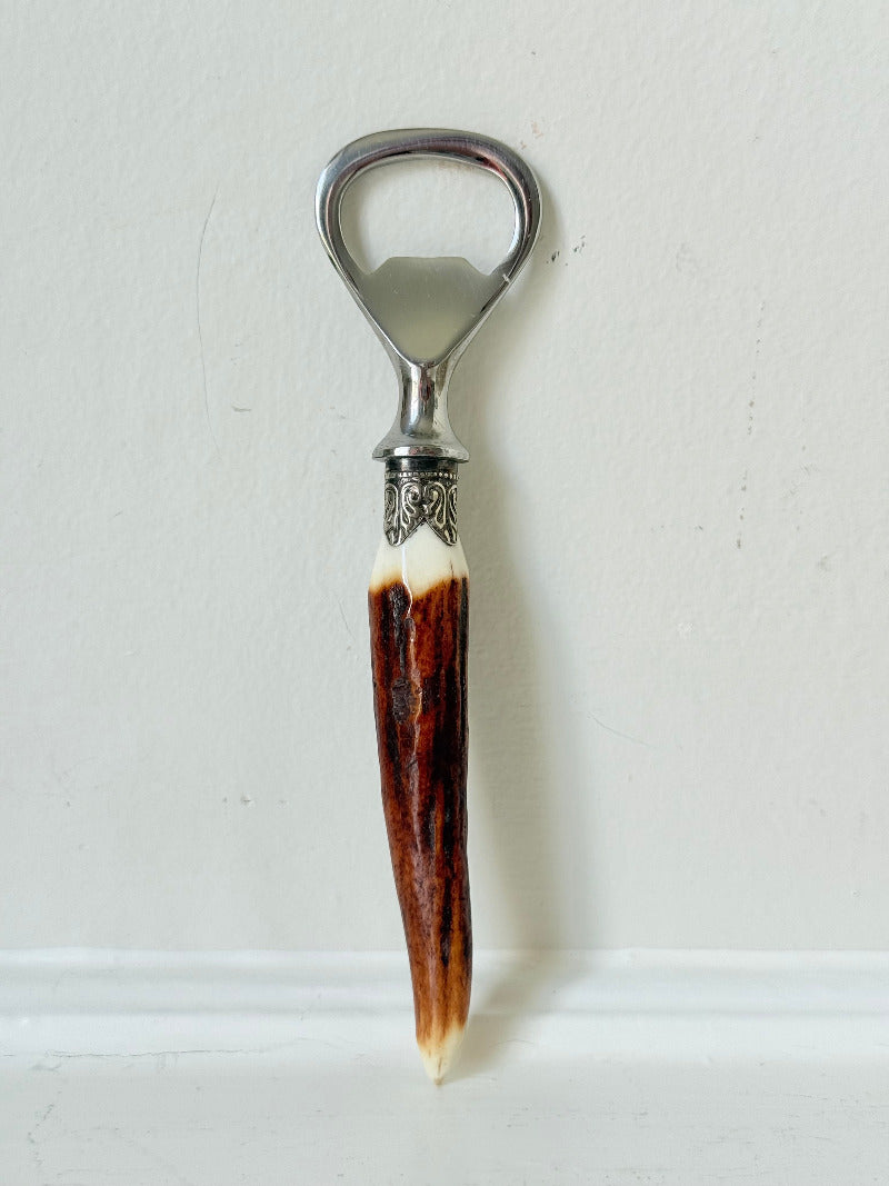 vintage antler handle bottle opener with stainless steel top photographed on white surface