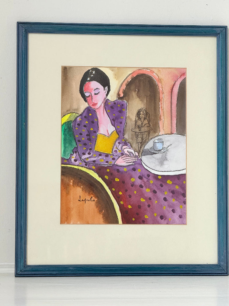Original watercolour portrait of Pamela in blue frame, vibrant interior scene, photographed on white surface