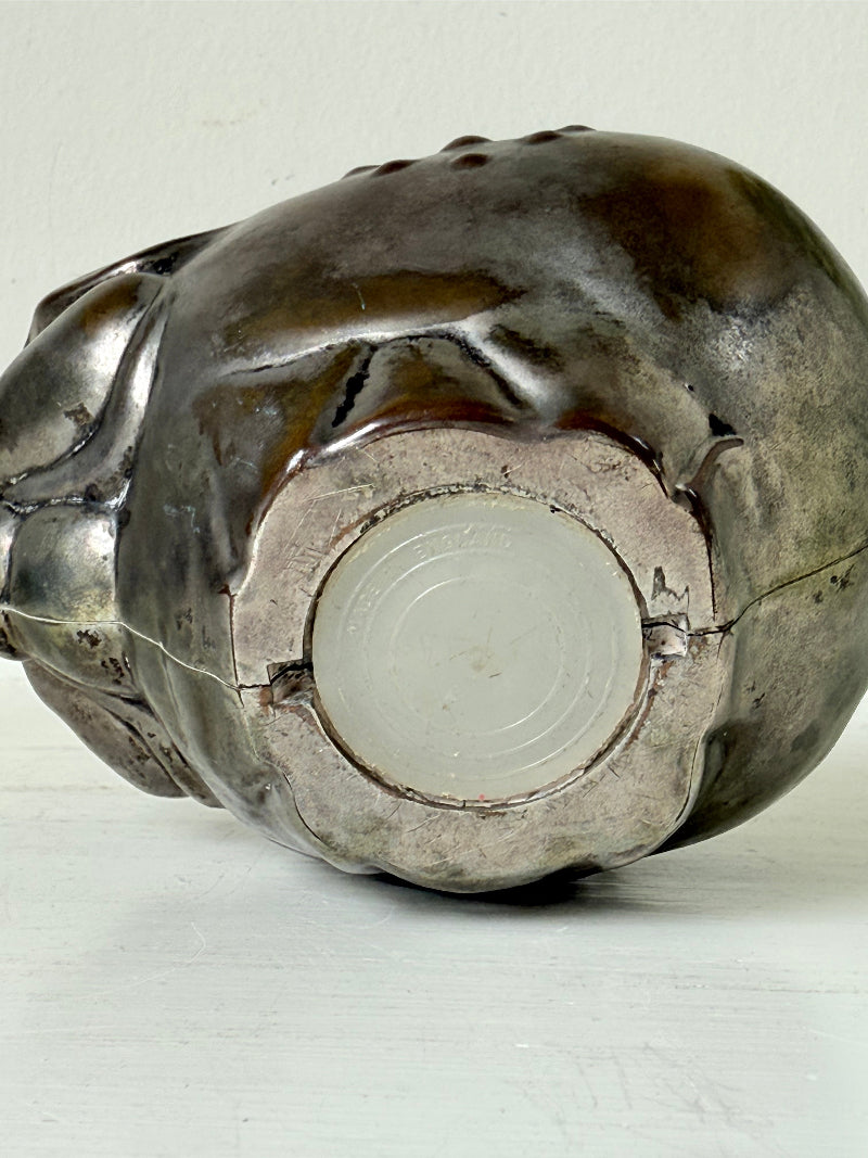 Vintage cast metal piggy bank in the shape of a pig with red painted eyes, photographed on a white surface