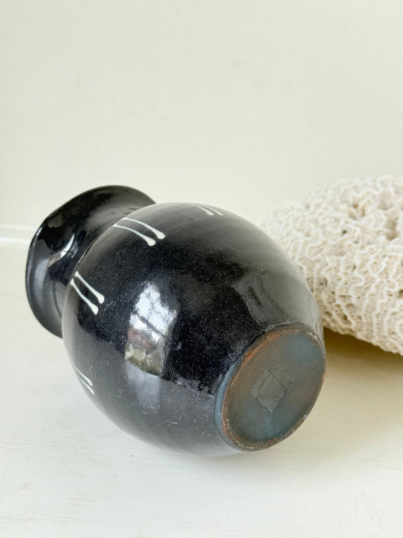Slipware studio pottery jug with blue glaze and terracotta handle, photographed on a white surface