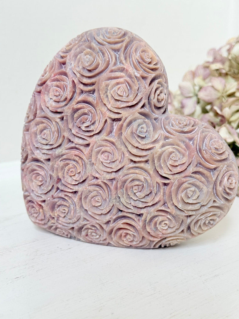 vintage pink stone heart with engraved roses and flat base on white surface