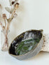 Studio pottery olive bowl with green and charcoal glaze, photographed on a white surface
