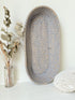 Vintage grey woven bread basket with oval shape and raised rim, photographed on white surface.