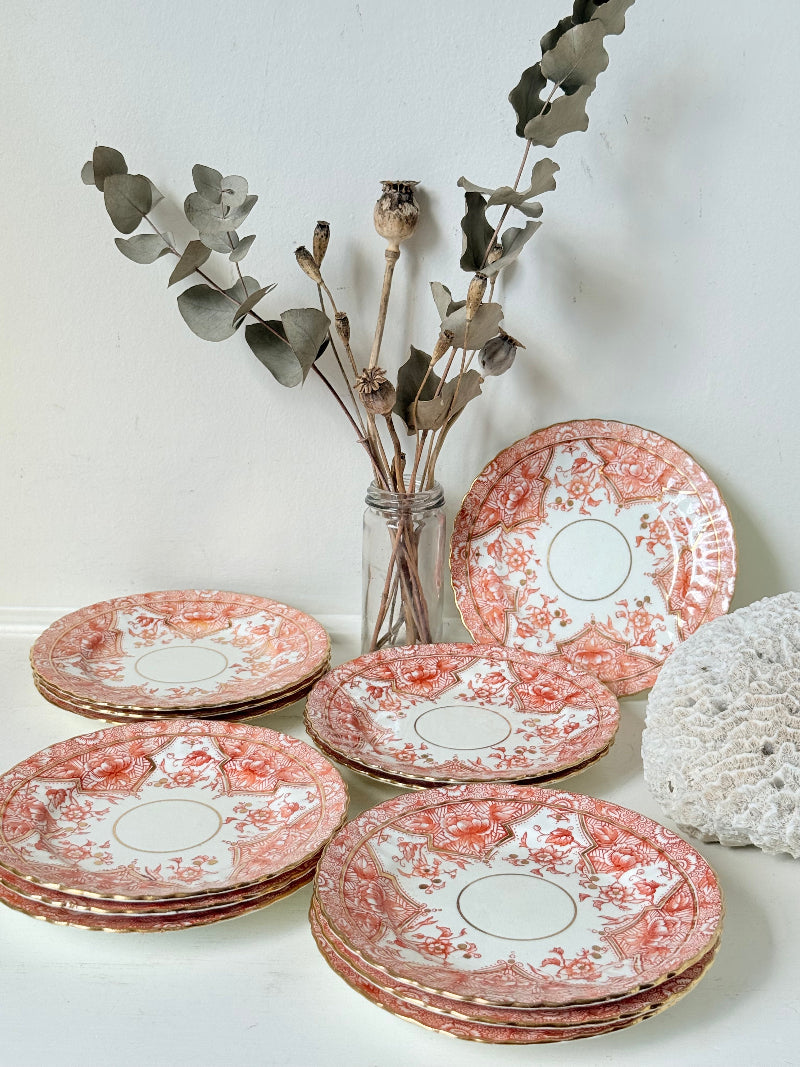 Set of 12 vintage coral transferware porcelain plates with scalloped edges and gold accents, 15 cm diameter, styled on a white surface.