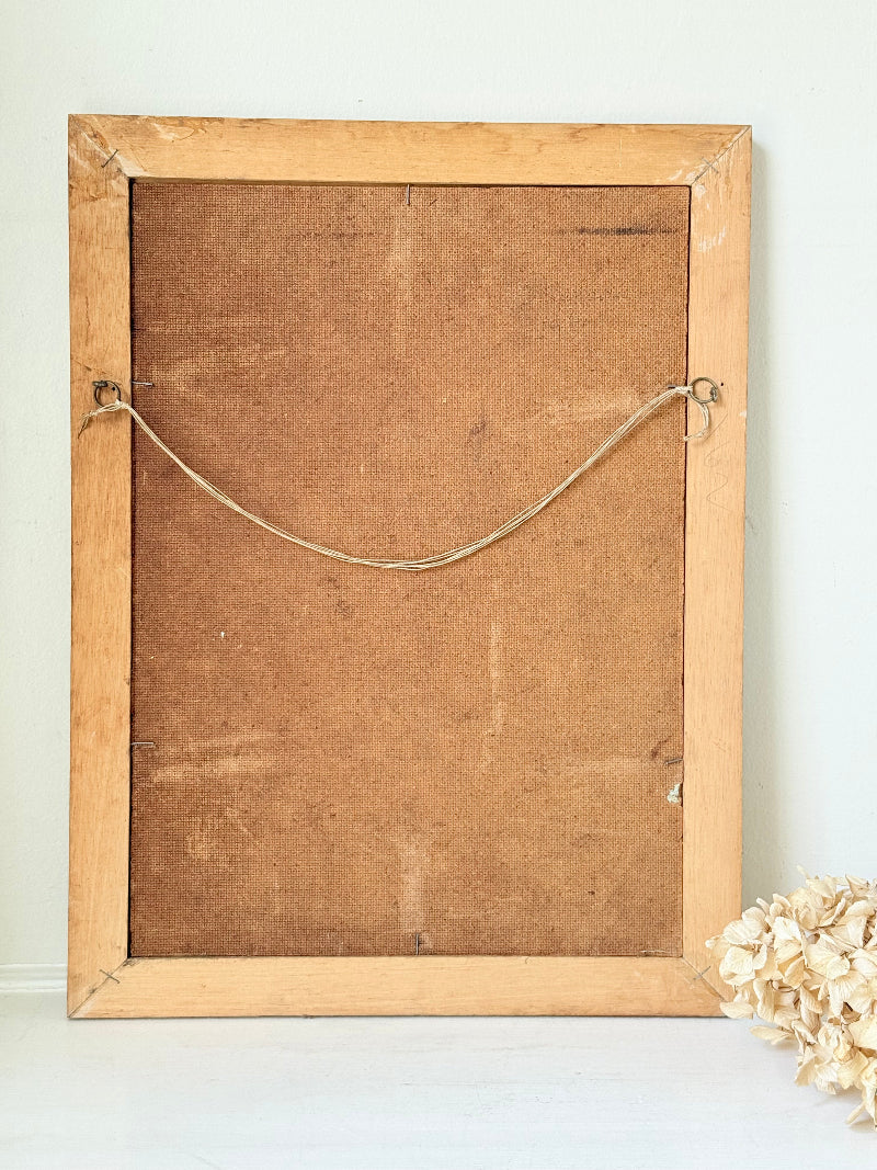 Vintage oil painting of cornflowers in a vase with yellow background in wooden frame photographed on a white surface