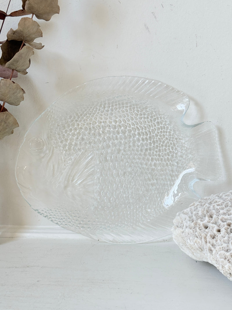 Vintage clear glass fish shaped serving dish with textured scale pattern photographed on a white surface