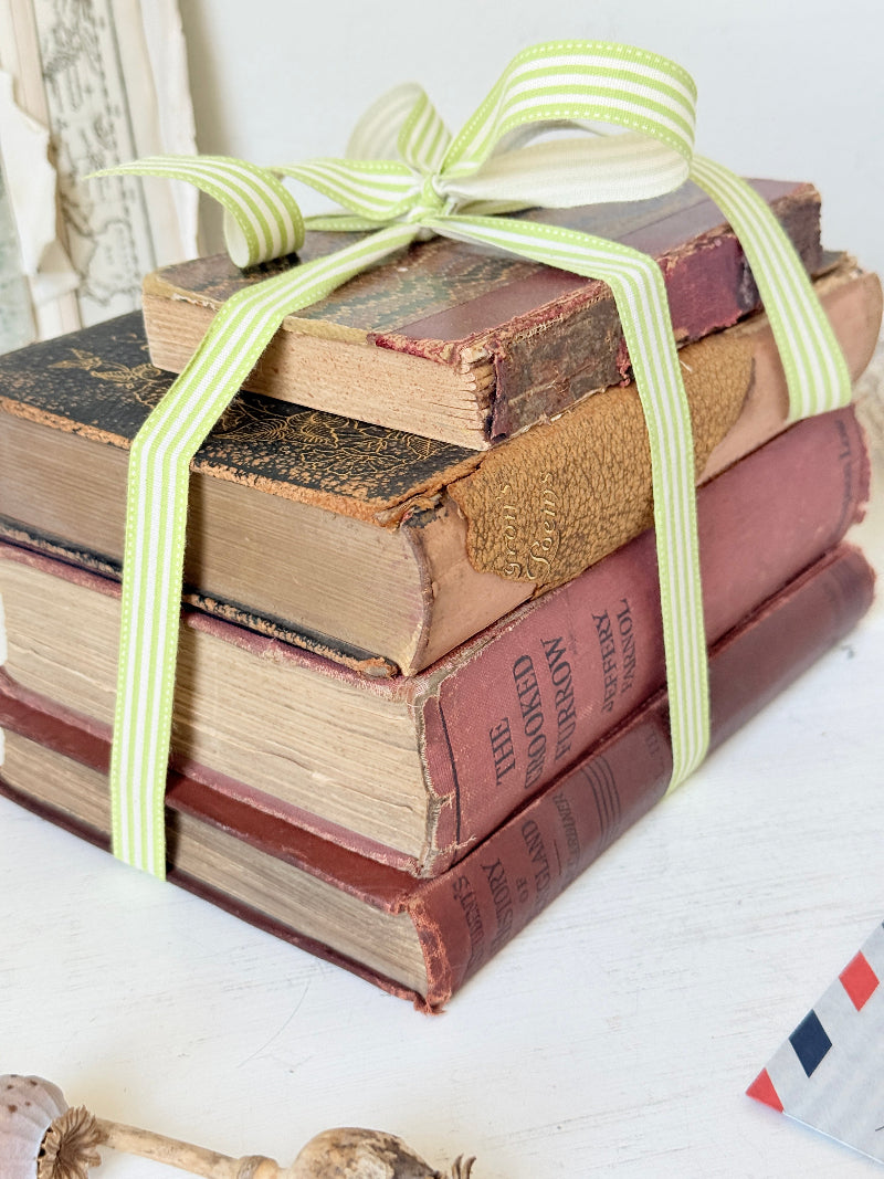 Vintage decorative book bundle with red burgundy cream and green hardback covers tied with green stripe ribbon for interior styling