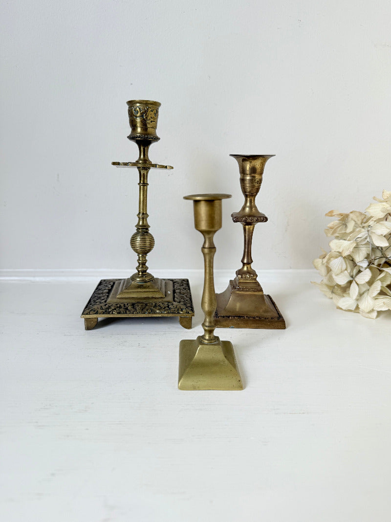 vintage brass trio of candlesticks in mixed designs photographed on white surface