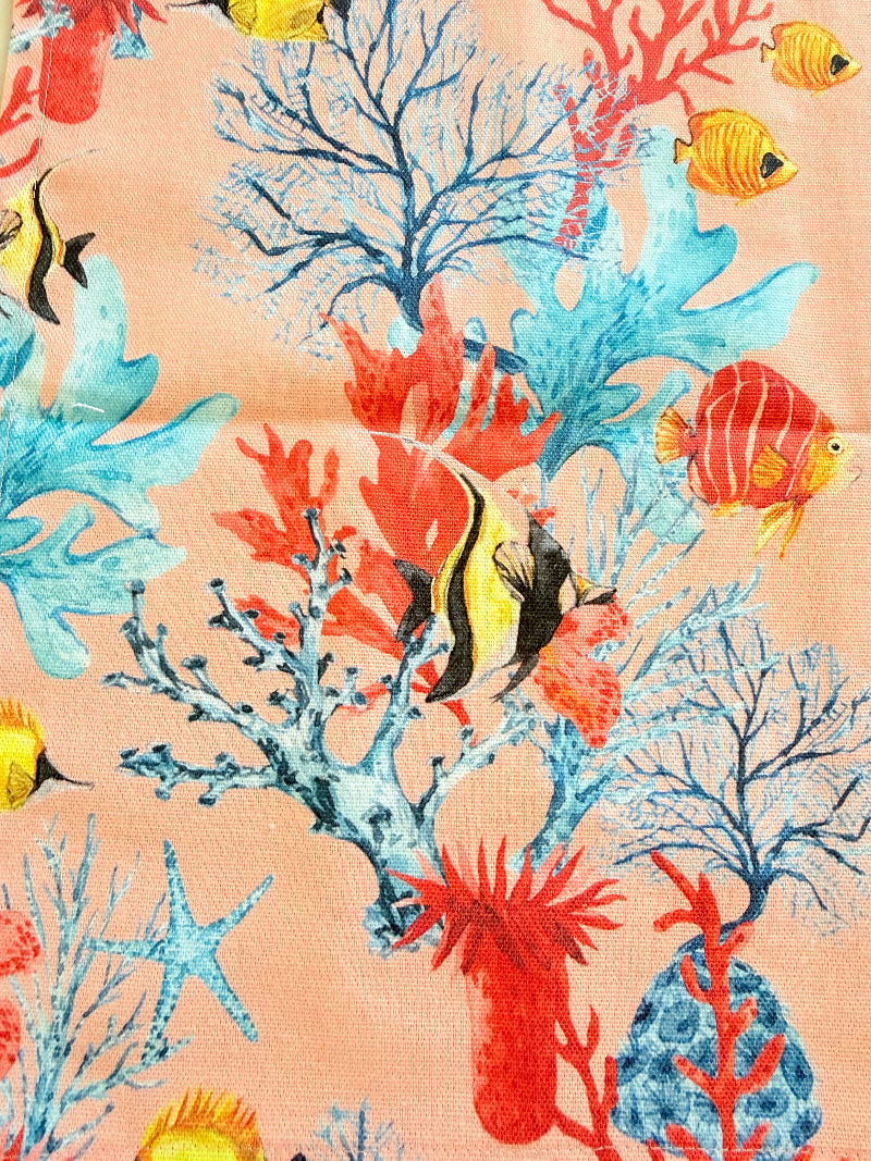 The Blue Loft coral reef cotton tea towels in coral pink and white with coastal inspired pattern photographed on a stone surface.