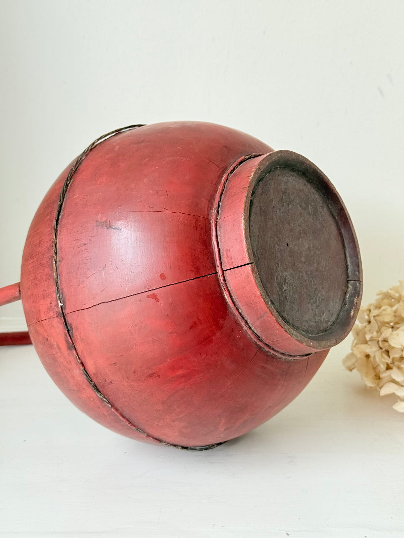 Vintage red painted wooden basket with tall curved handle and domed lid photographed on a white surface