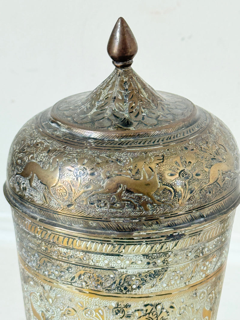 Indian Benares brass jar with lid and engraved animals and floral design, photographed on a white surface