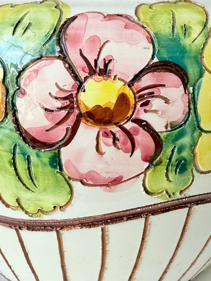 Large European hand painted floral ceramic jardinière with yellow, pink and green flowers on a white base, styled on a white surface with dried foliage.