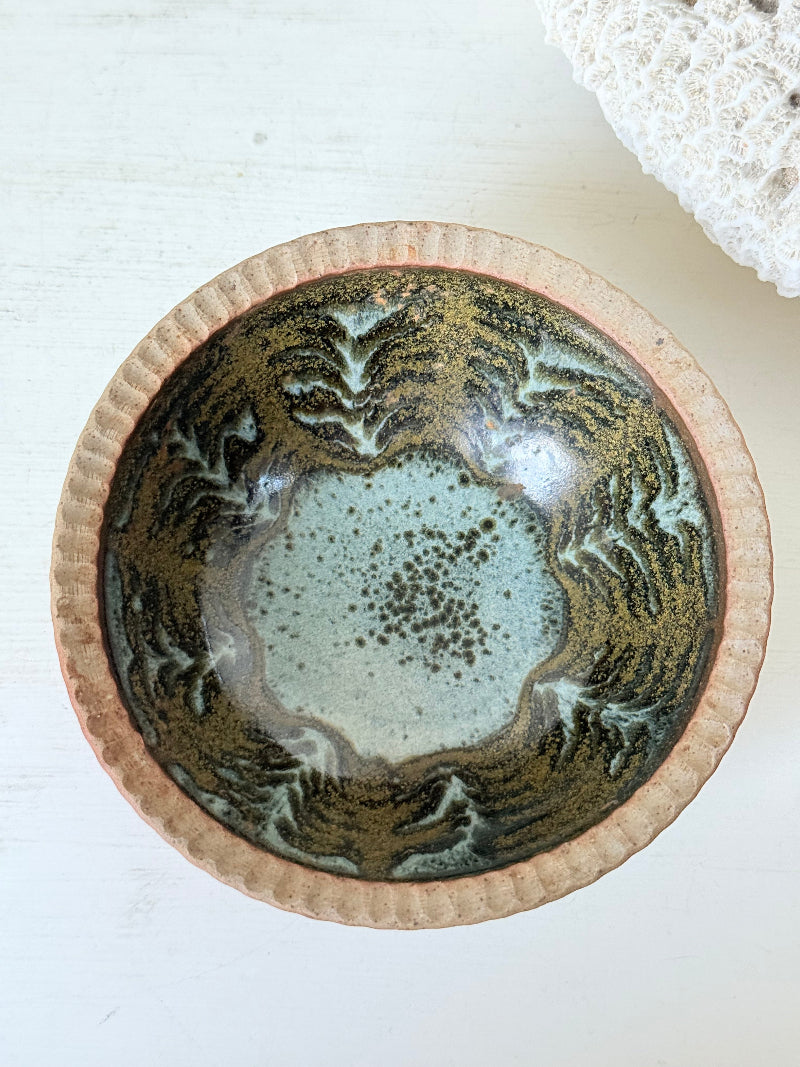 Benjamin Eeles studio pottery stoneware bowl with green and blue glazed interior on a white surface.