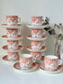 Vintage coral transferware coffee cans and saucers with scalloped edges and gold accents, set of ten, styled on a white surface.