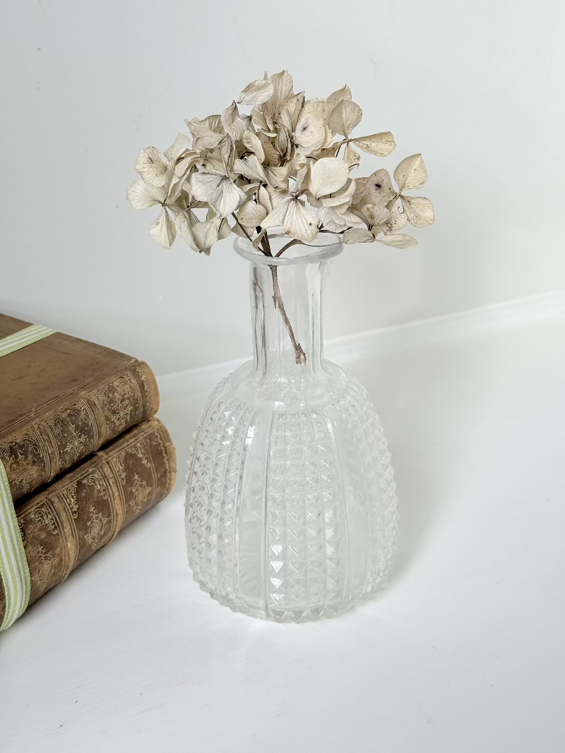 Vintage clear glass vase with textured surface, styled with dried flowers on a white background